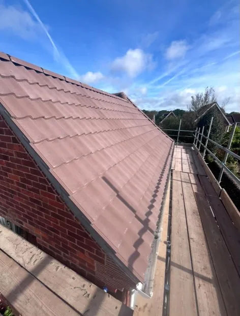 new fascia and roof edge finishing on a brick house with scaffolding in Godalming — Mitchell's Roofing