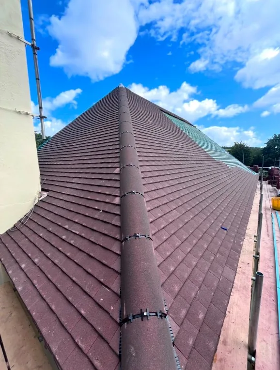 new dark clay tile roof valley with chimney and scaffolding in Yateley — Mitchell's Roofing